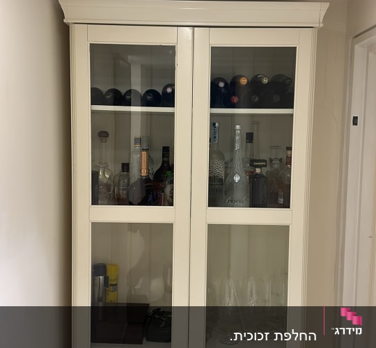 ארון תצוגה לבן עם דלתות זכוכית לאחסון בקבוקים וכוסות